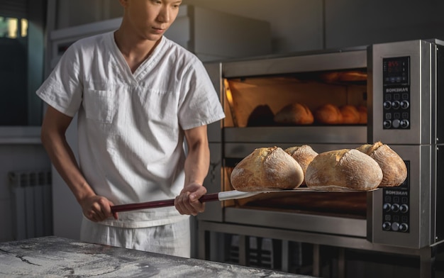 The baker is a man in the process of baking bread Production of bakery products as a small business