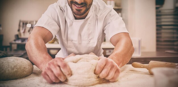 Фото Бейкер замешивает тесто у стойки на коммерческой кухне