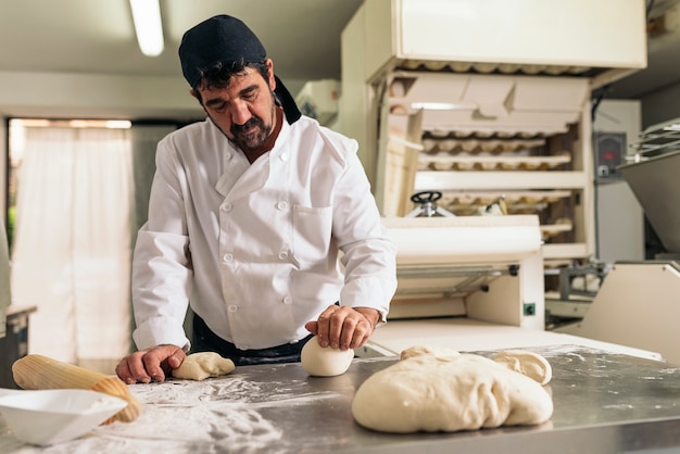 Baker kneading dough in a bakery. Bakery Concept.