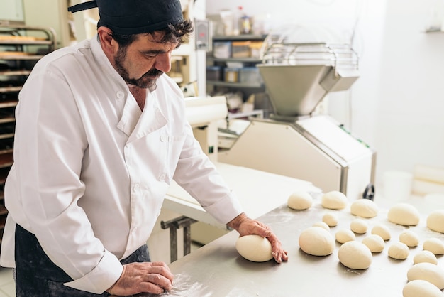 Baker kneading dough in a bakery. Bakery Concept.