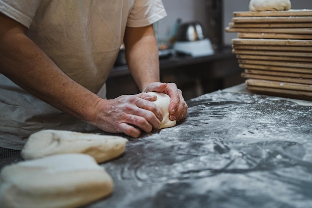 Baker kneedt brooddeeg op een rommelige toonbank vol meel in de bakkerij