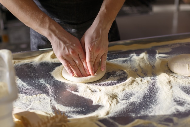 Baker kneedt deeg voor pizza in de keuken in het restaurant