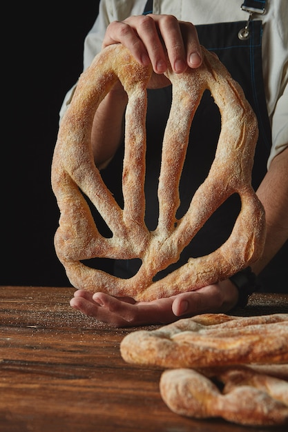 Baker legt vers gebakken fougas brood op een houten bruine tafel