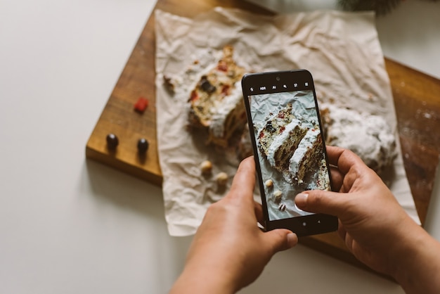 Baker maakt een foto van de gebakken kerststol op een mobiele telefoon