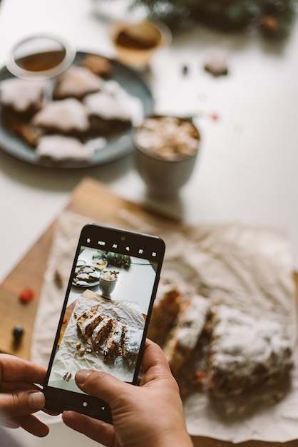 Baker maakt een foto van de gebakken kerststol op een mobiele telefoon