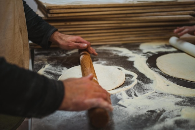 Baker maakt pizzadeeg plat met deegroller om het daarna te koken