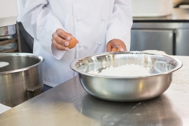 Baker making dough with eggs and flour