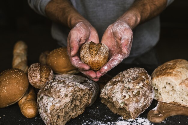 Foto uomo del panettiere che tiene una pagnotta organica rustica di pane nelle sue mani