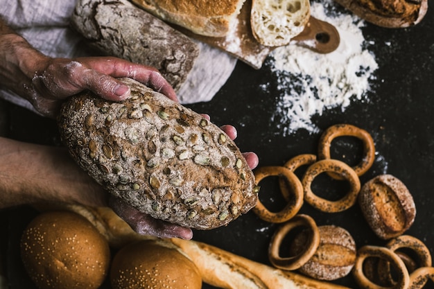 Foto uomo del panettiere che tiene una pagnotta organica rustica di pane nelle sue mani