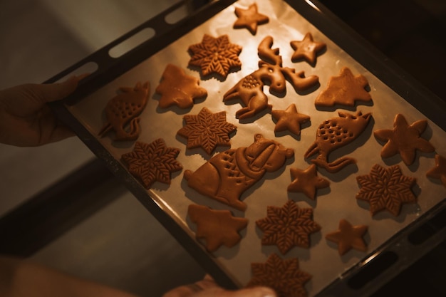 Baker plaatst een bakplaat met peperkoekkoekjes in de oven