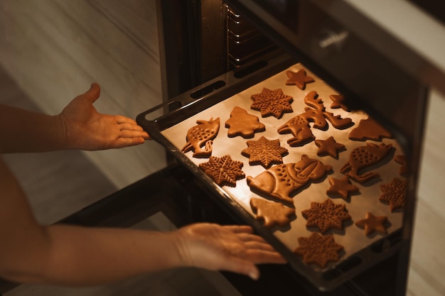 Photo baker places a baking sheet with gingerbread cookies in the oven