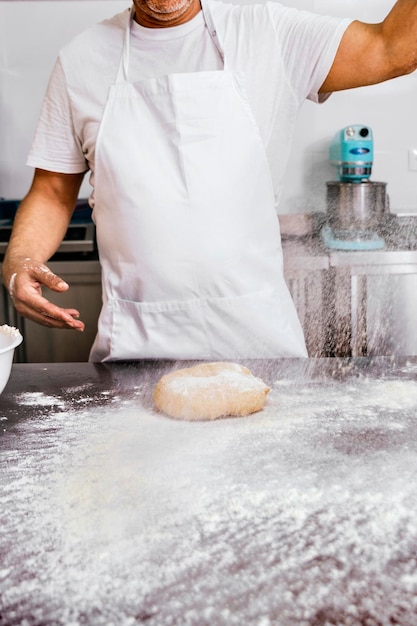 Baker pouring flour on a bread dough on a workbench