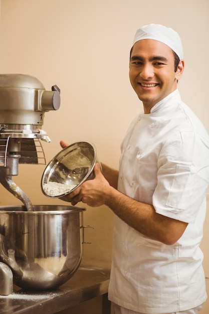 Baker pouring flour into large mixer