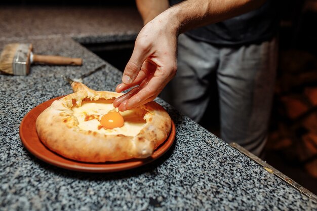 Baker's hands preparing khachapuri on kitchen table