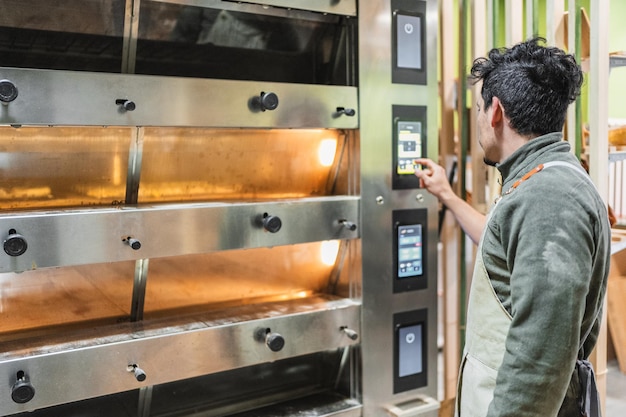 Baker setting temperature of industrial oven in bakery