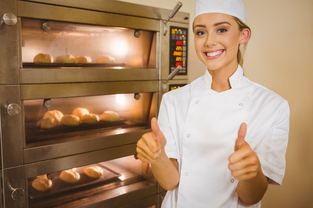 Baker smiling at camera beside oven