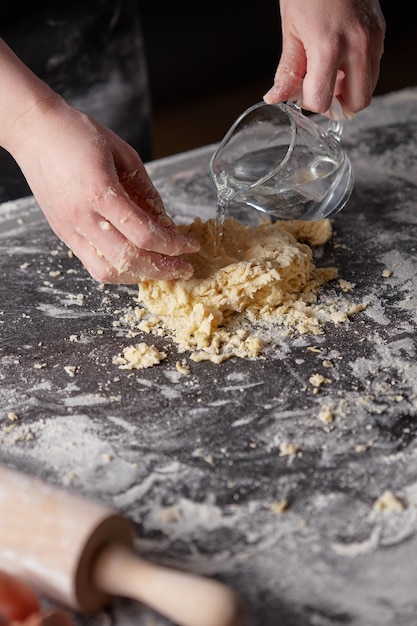 Baker vrouw toe te voegen water kneedt deeg voor het bakken