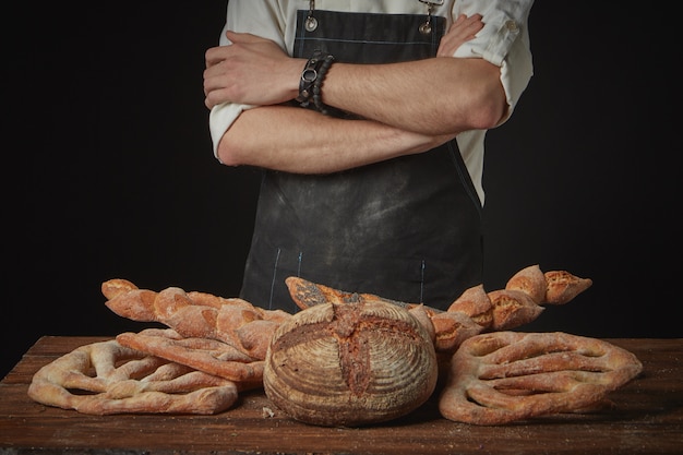 Baker with assortment of organic bread on a brown wooden table