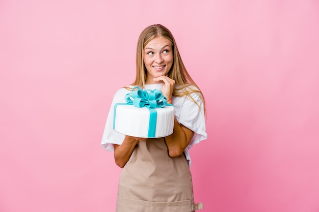 baker woman holding a delicious cake keeps hands under chin