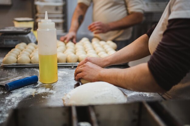 Baker woman kneading bread dough at kitchen in artisan bakery