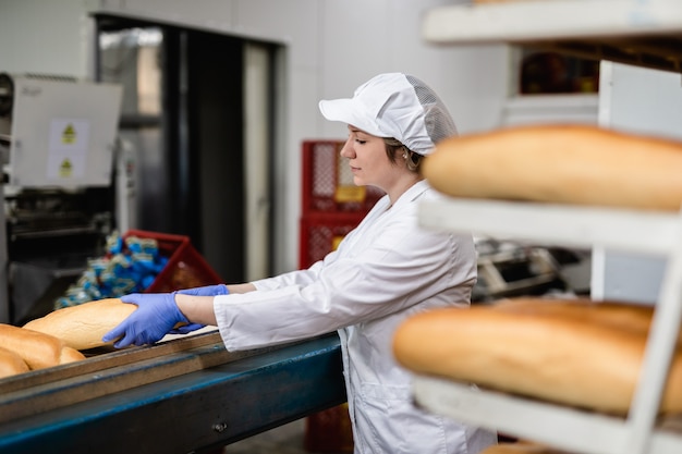 Donna del panettiere che lavora alla linea di produzione del pane.