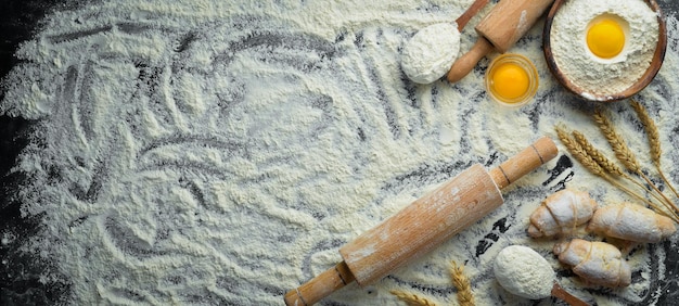 Sfondo di panetteria uova di farina mattarello per impasto su sfondo nero vista dall'alto spazio libero per il testo