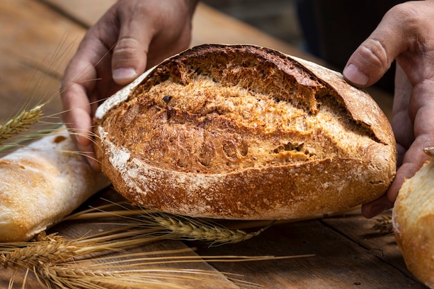 Bakery background. Fresh crunchy loaf of bread in the hands of a baker close up