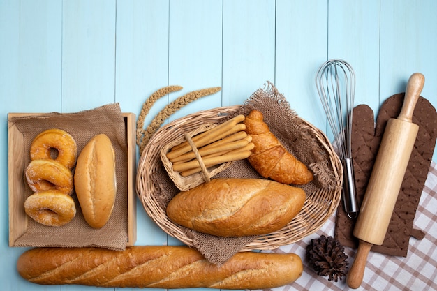 Bakery Bread on blue Wooden Table. Various Bread and Sheaf of Wheat Ears.