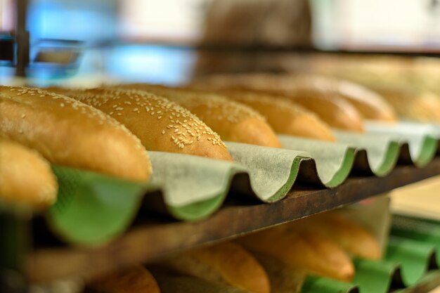 Bakery, bread.fresh buns with sesame on tray rack from side view.