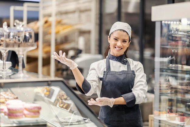 A bakery department saleswoman presenting sweets in supermarket