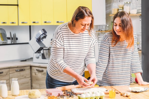 Bakery food and pastry cooking Mother teaching daughter how to work with dough make gingerbread biscuits