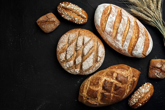 Bakery gold rustic crusty loaves of bread and buns on black chalkboard background