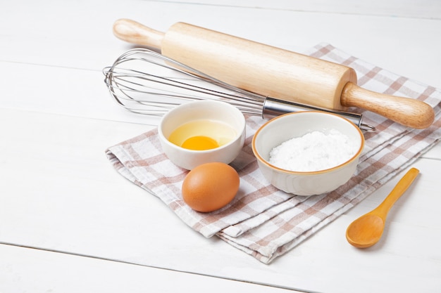 Bakery ingredients. wheat ears and bowl of flour, egg, rolling pin, egg whisk, Oven glove on white