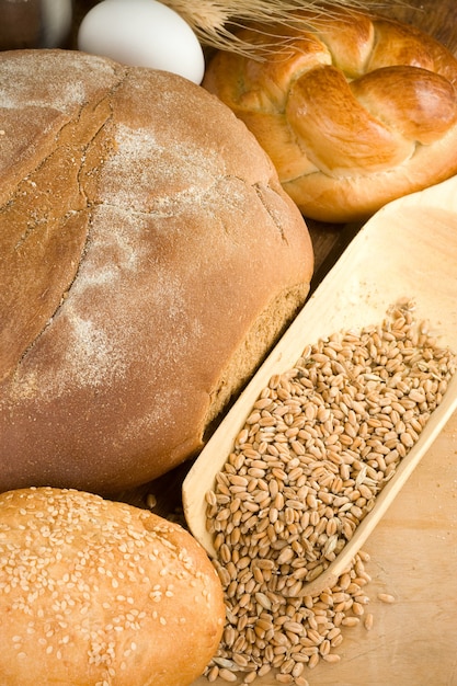 Bakery products and wheat grain on wooden texture