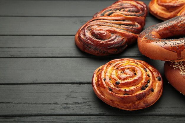 Photo bakery various kinds of breadstuff bread rolls bagel sweet bun on black wooden background space for text