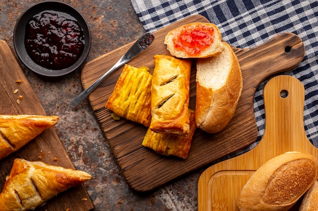 Photo bakery various kinds of fresh fragrant baked bread in wooden cutting board on table napkin top view flat lay food theme design concept