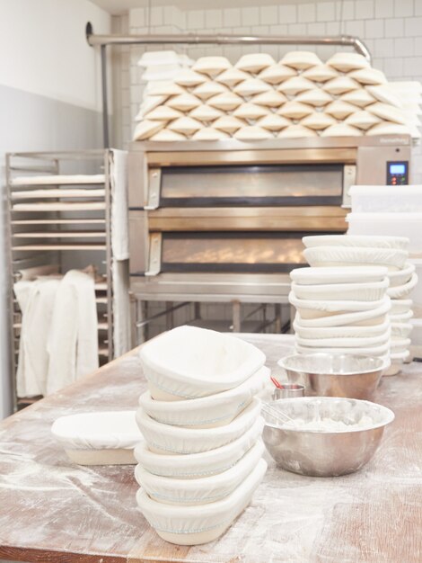 bakery work table for kneading bread with stacked bread pans and flour bowls ovens