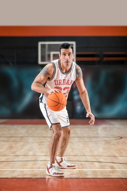 Baket-ball-speler. Donkerharige atletische man basketballen in de sportschool