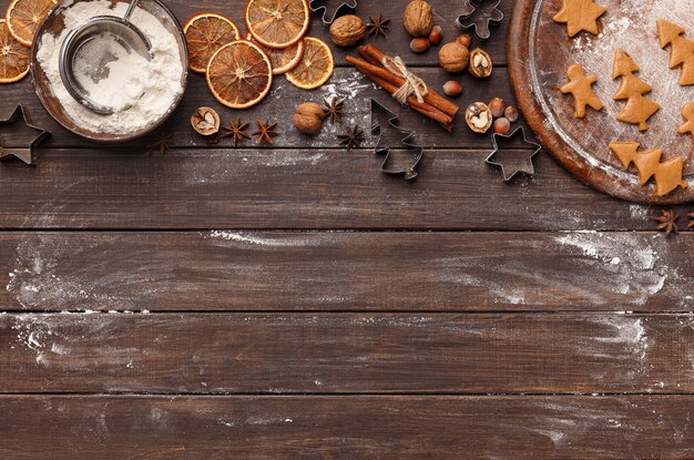 Baking background. Gingerbread cookies, flour and christmas spices on wooden table, copy space, top view