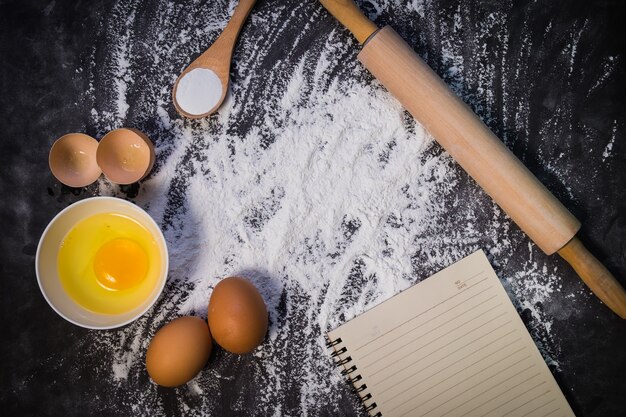 Baking background with the rolling pin with flour. On the dark table. 