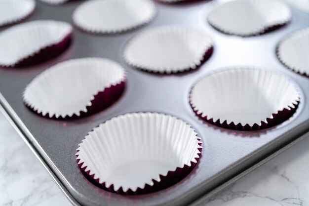 Baking chocolate cupcakes. Lining metal cupcake pan with foil cupcake liners.