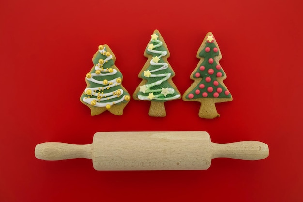 Baking concept with a selection of glazed cookies with rolling pin over a festive red background