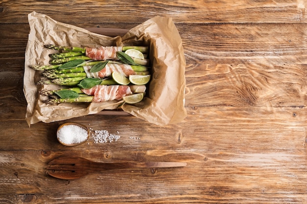 Foto teglia da forno con pancetta avvolta asparagi sul tavolo di legno