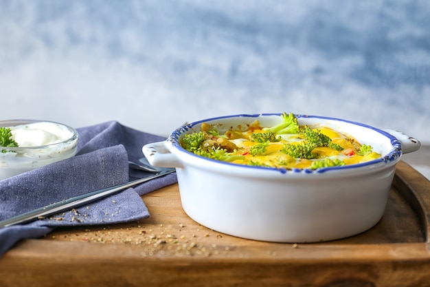 Baking dish with broccoli casserole on wooden board