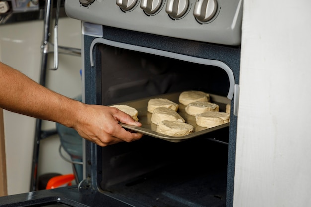 Baking at home Putting a tray with biscuits in the oven from the stove