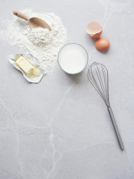 사진 베이킹 재료: 달, 밀가루, 우유, 버터, 회색 테이블, 손으로 만든 금속 휘파람