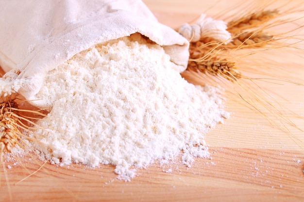 Baking ingredients: flour and ears on a light wooden background