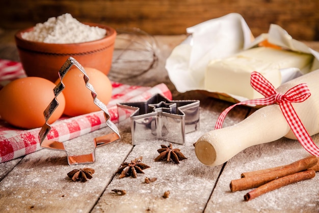 Baking ingredients flour eggs butter and rolling pin cookie cutters on a table