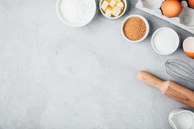 Baking ingredients Flour eggs sugar butter roller pin and whisk on the kitchen table Top view copy space