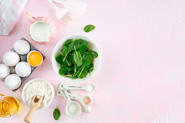 Baking ingredients and kitchen utensils on a pink background top view